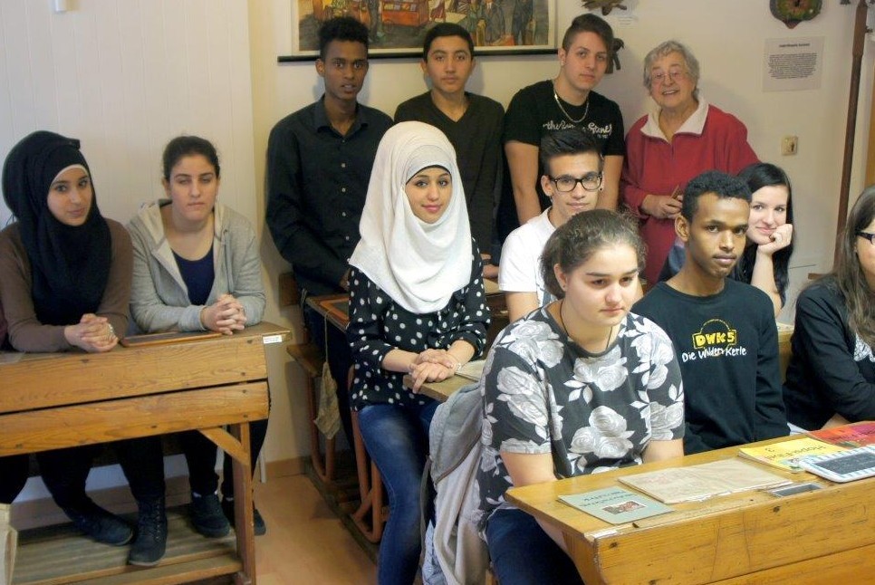 Kinder sitzen auf alten Schulbänken